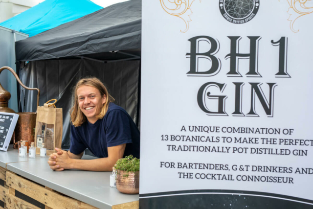 BH1 Gin trader smiling for the camera at his stall on the promenade