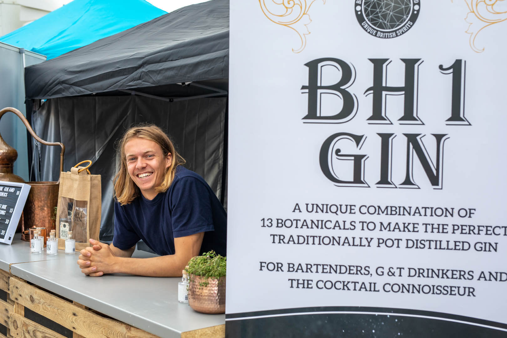 BH1 Gin trader smiling for the camera at his stall on the promenade