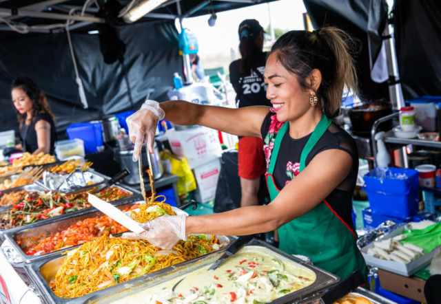 Trader dishing up and showing off her delicious array of Asian food at her stand