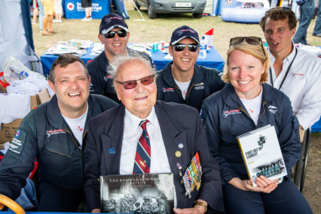 Pilots having their photo taken with a world war pilot veteran at the RAF village