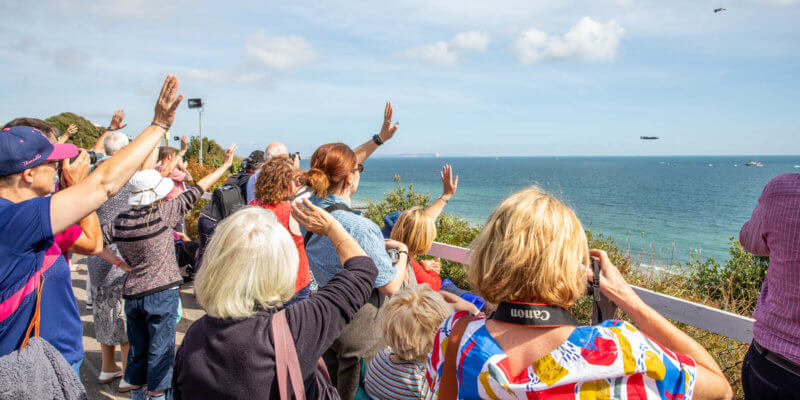 Onlookers waving at the planes as they soar through the beautiful sunny skies