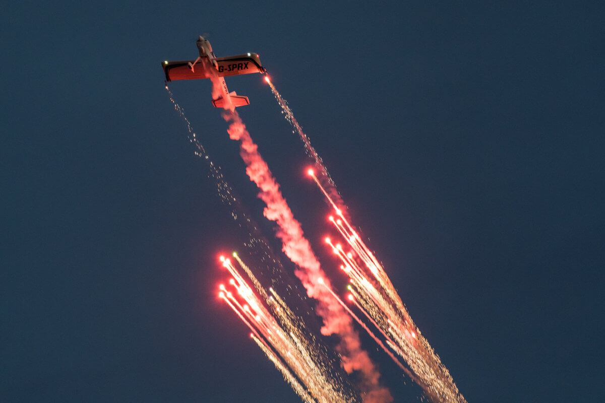 Fireworks flying off the fireflies plane during a dusk performance at the air show