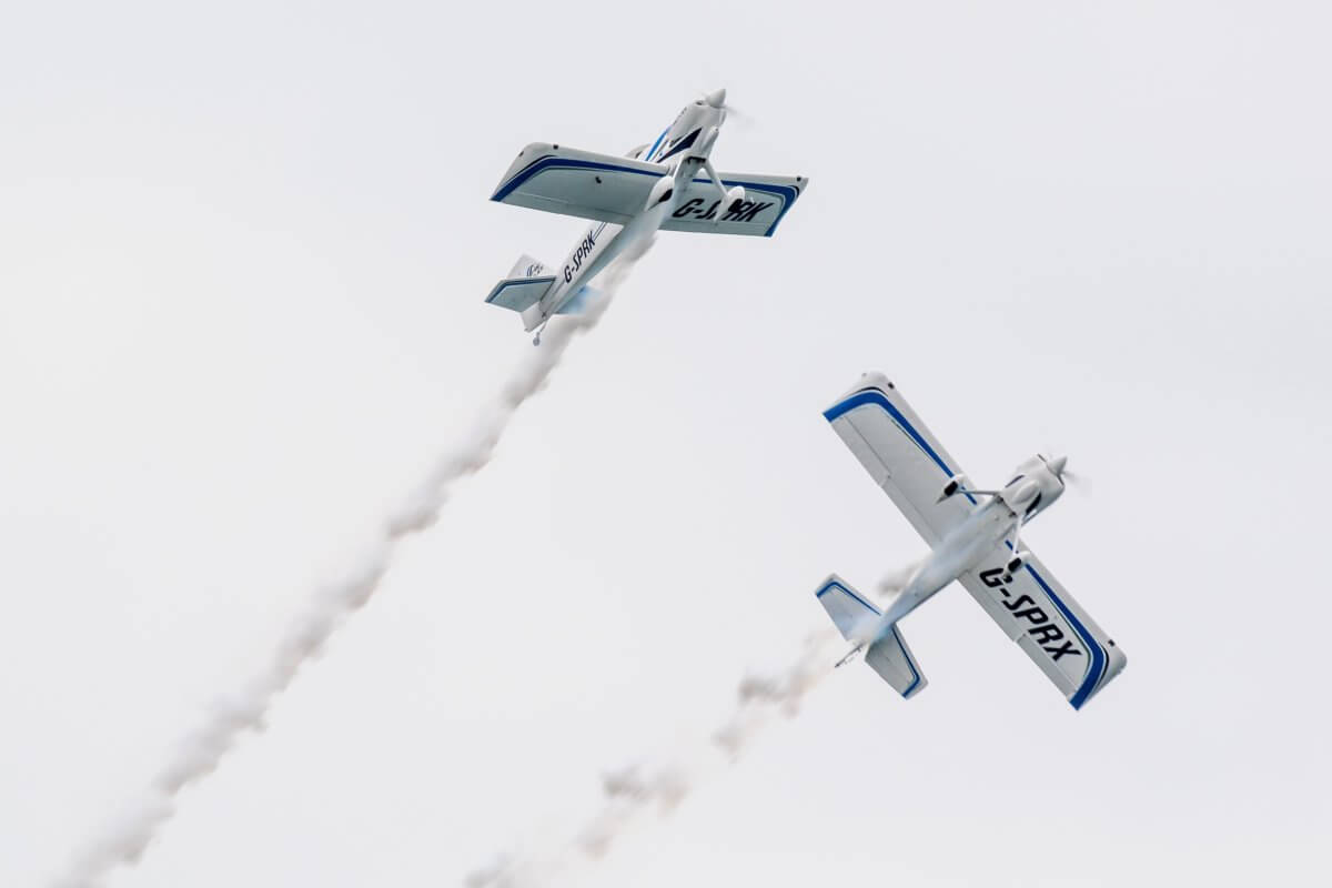 Two white and blue planes split of in the air