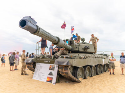 Army and a tank on the beach witth festival visitors