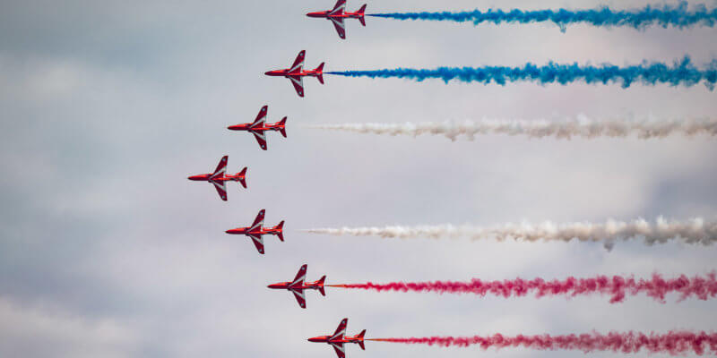 red arrows flying in formation with smoke coming out