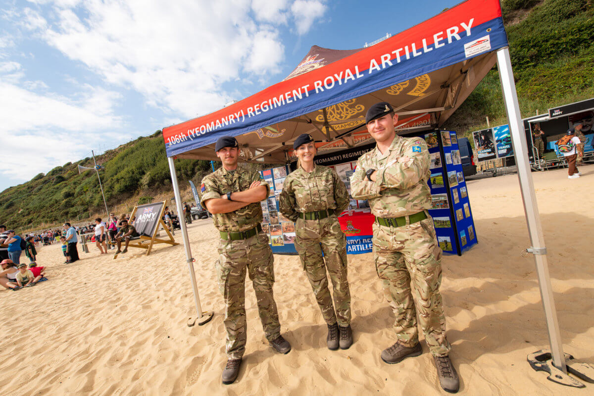 3 army men with arms crossed smiling for camera on Bournemouth beach